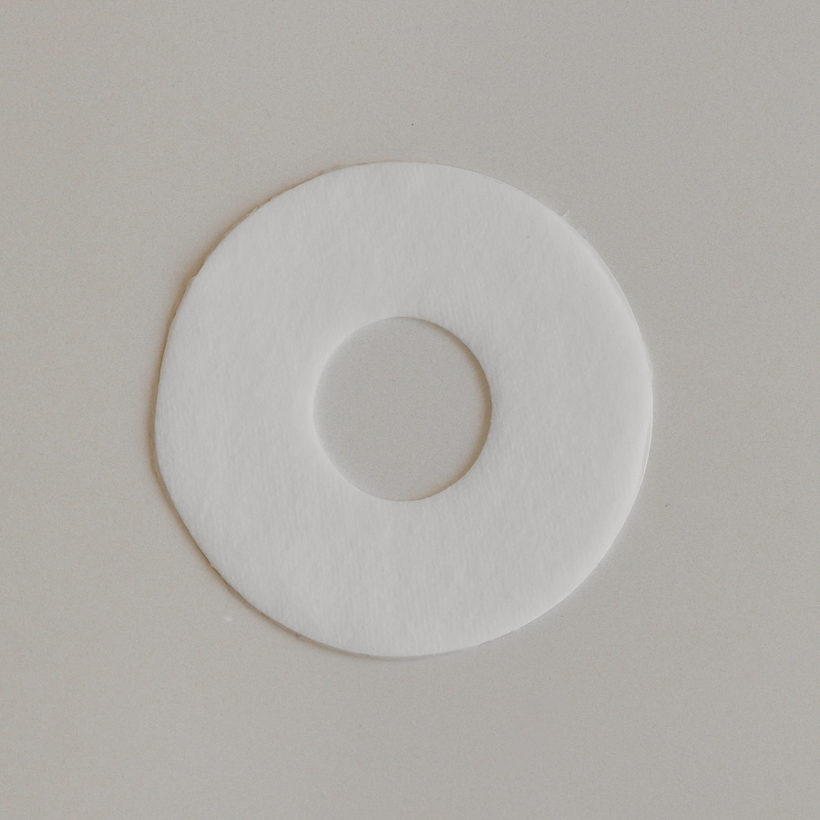 A white circular Bosom Ritual™ Discs with a hole in the center on a plain background.