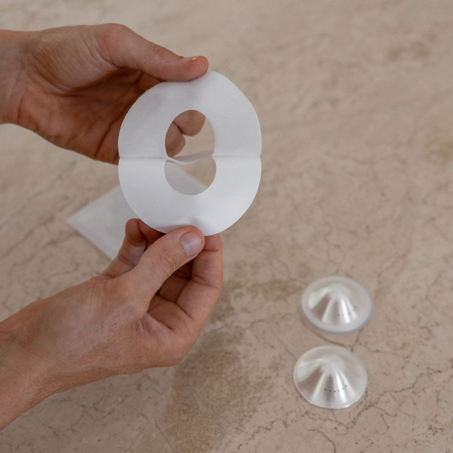 Mother peeling back the mammae aloe infused hydrogel adhesives with breathable silver cups on travertine kitchen bench