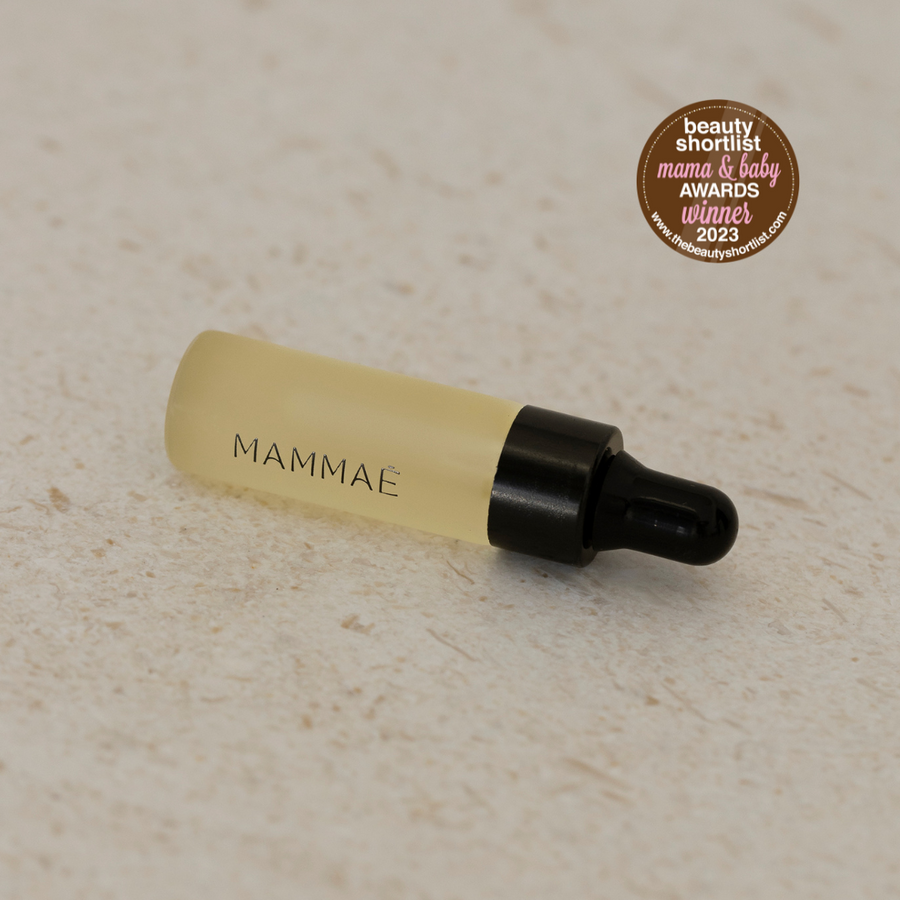A bottle of Bosom Ritual Elixir Deluxe Sample 5ml by Mammae The Embodied Mother, infused with herbal extracts, placed on a clean white surface during breastfeeding season.