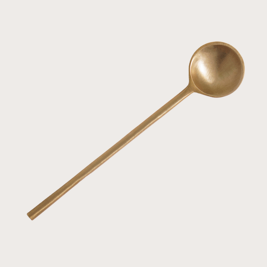A Ritualware Brass Teaspoon from Mammae The Embodied Mother gently rests on a pristine white background.