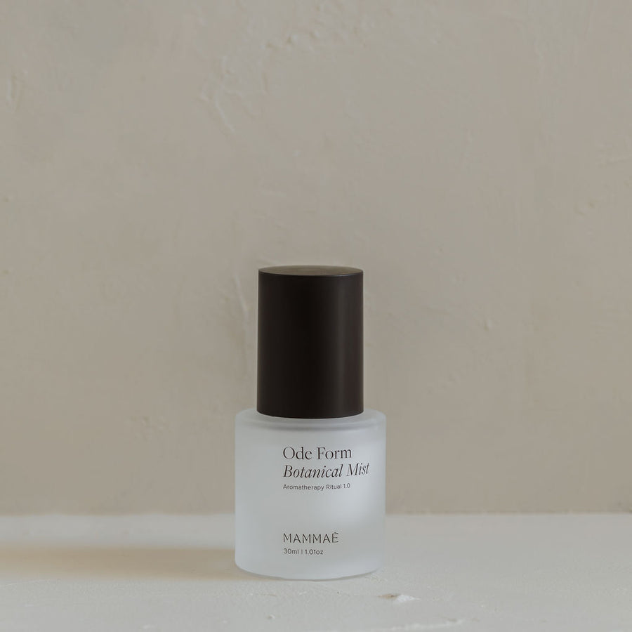A bottle of Mini Ode Form™ Botanical Mist with a white cap sitting on a white surface, used for an aromatherapy ritual by Mammae The Embodied Mother.
