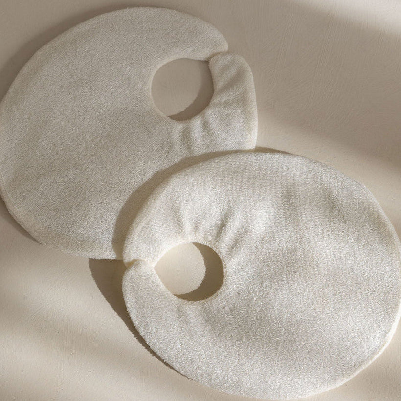 Two natural eco-friendly bamboo reusable fabric covers on a beige background with soft shadows of the Mammae hot and cold packs for breastfeeding and lactation support. 