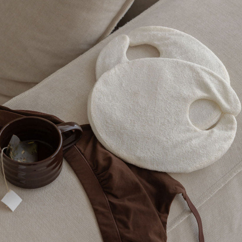 Mammae Breast Pack for lactation support resting on a beige surface with a cup of nursing tea and chocolate brown bra. 