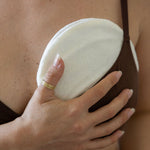 Postpartum mother wearing a chocolate brown nursing bra holding a white bamboo cover with a hot and cold breast pack inside for breastfeeding and postpartum relief. 