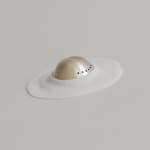 Minimalist representation of a hat using a flat white surface and a three-dimensional semi-spherical object with Mammae The Embodied Mother Bosom Ritual™ Discs details.