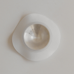 Stainless steel sink strainer on a white surface with Bosom Ritual™ Discs by Mammae The Embodied Mother adhesives.
