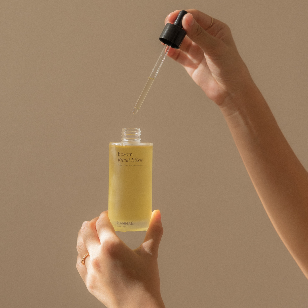 A person holding a bottle of Bosom Ritual™ Elixir for postpartum breast care and breast inflammatory conditions such as mastitis, engorgement, breast pain, blocked milk ducts, low milk supply.