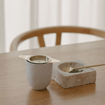 A Bosom Ritual™ Infusion tea and spoon for Breast Care during Pregnancy and Postpartum on a wooden table by Mammae The Embodied Mother.