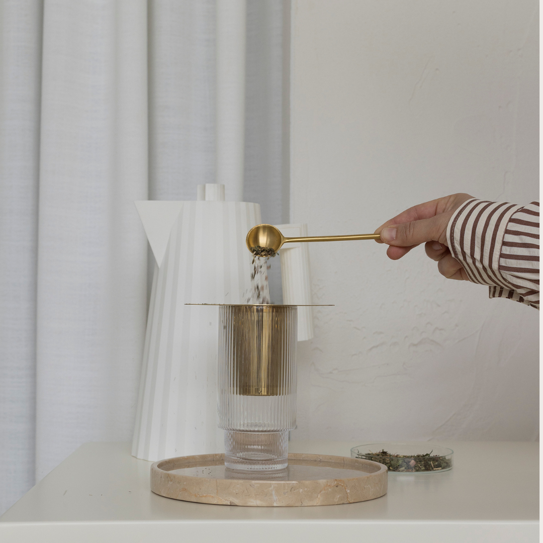 A person pouring a cup of coffee into a glass, experiencing lactation wellness with the help of Bosom Ritual™ Infusion by Mammae The Embodied Mother.
