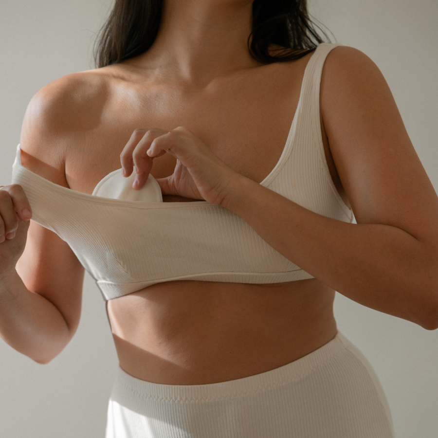 A woman wearing the white certified organic Bosom Wearables breast pads by Mammae, designed for breastfeeding and supporting lactation.