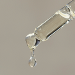 A drop of Mini Bosom Ritual™ Elixir is coming out of a glass tube from Mammae The Embodied Mother.