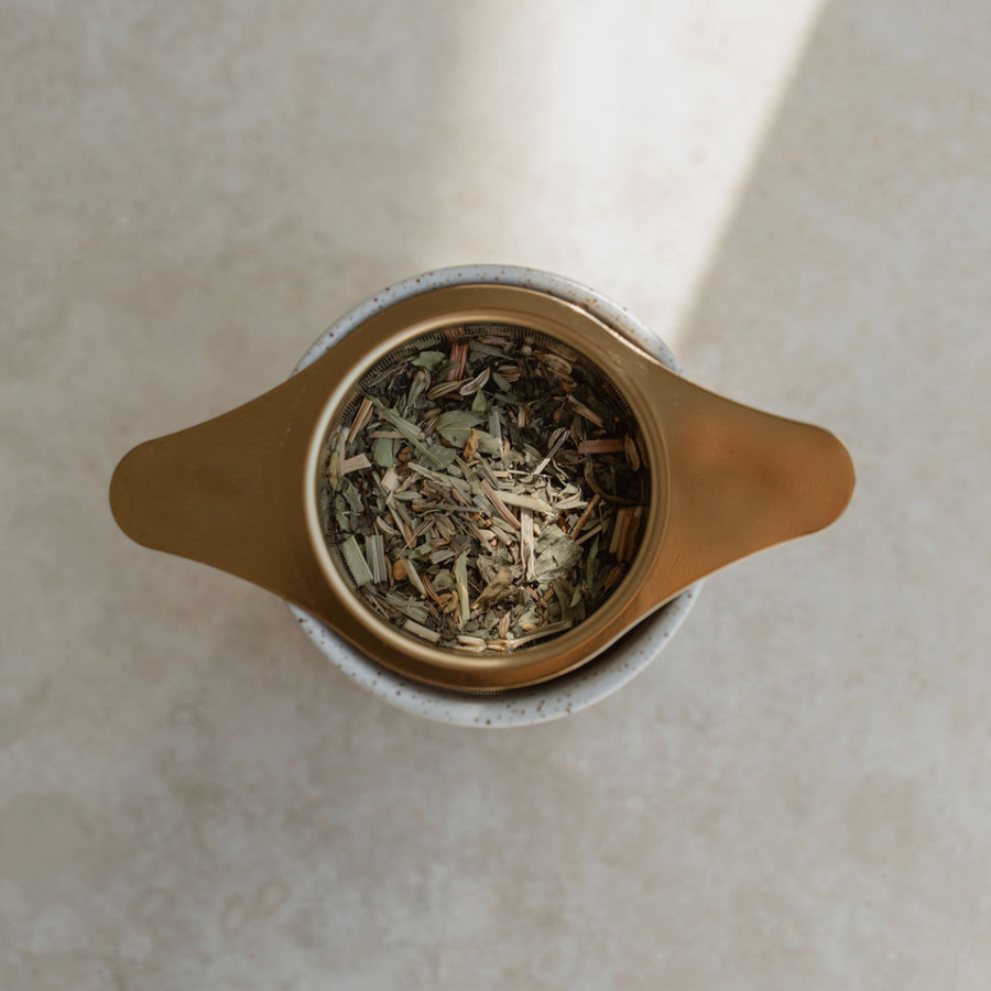 A Ritualware Tea Infuser filled with herbs, perfect for pregnancy and breastfeeding, adorned on a white surface.