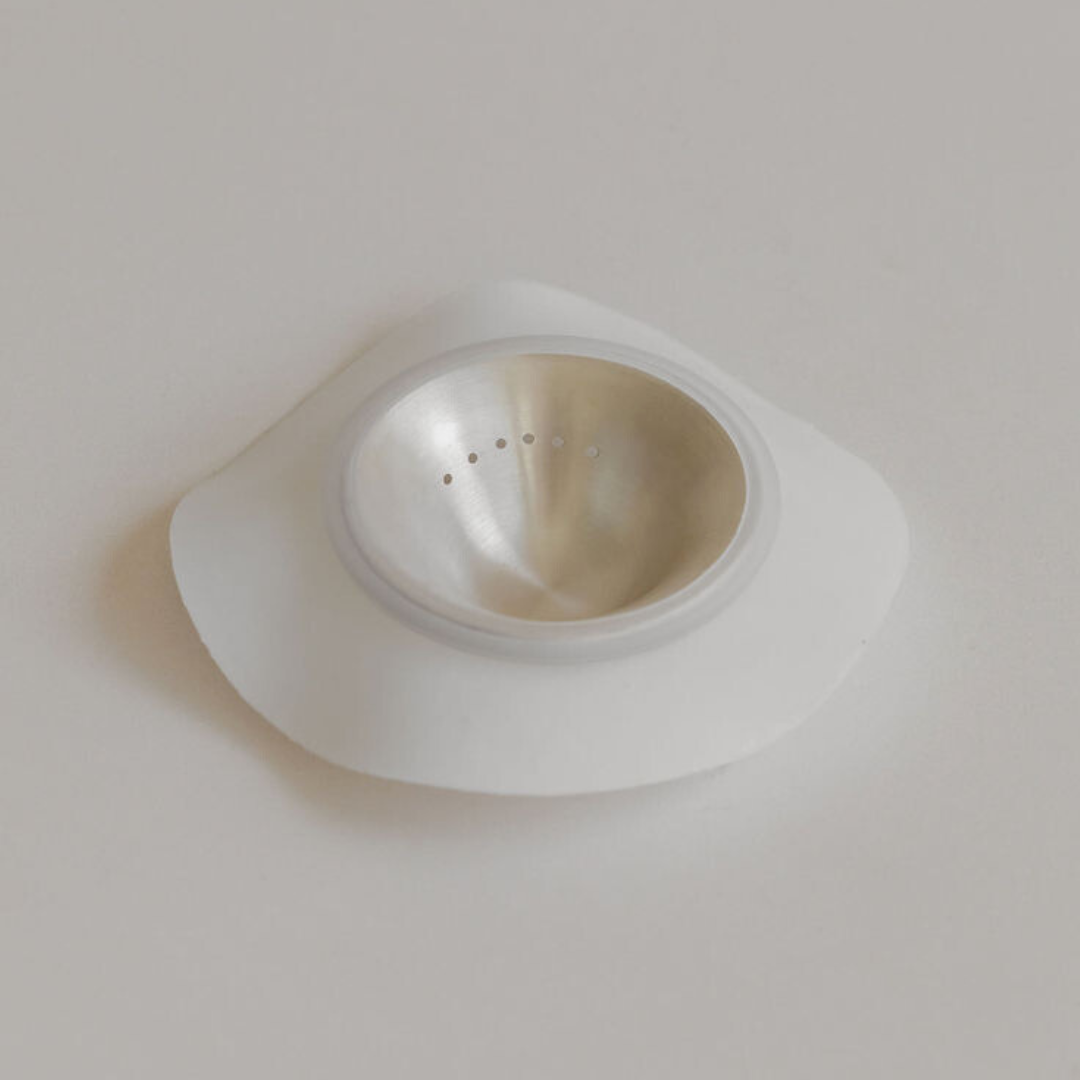 Silver nursing cup inside the hydrogel adhesive by Mammae on neutral backdrop. 